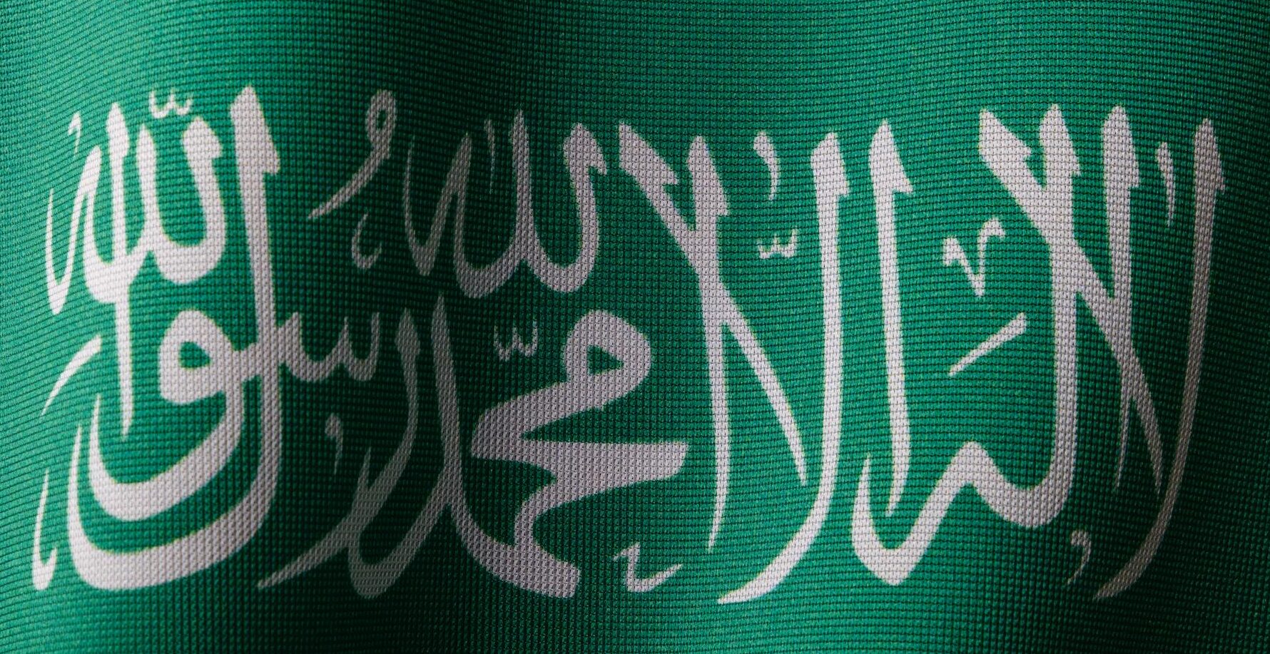 Detailed close-up of the Saudi Arabian flag showcasing the elegant Arabic script and vibrant green color.
